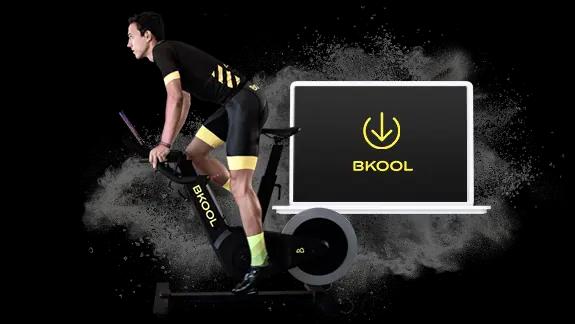 Cyclist training on an indoor cycling bike and computer with the download logo of the BKOOL indoor cycling applications.