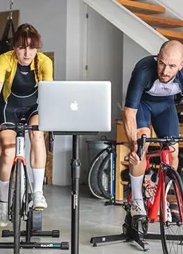 Ciclisti che si allenano a casa con un simulatore di indoor cycling