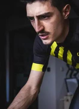 Ciclista che guarda il suo computer mentre si allena con un simulatore di indoor cycling